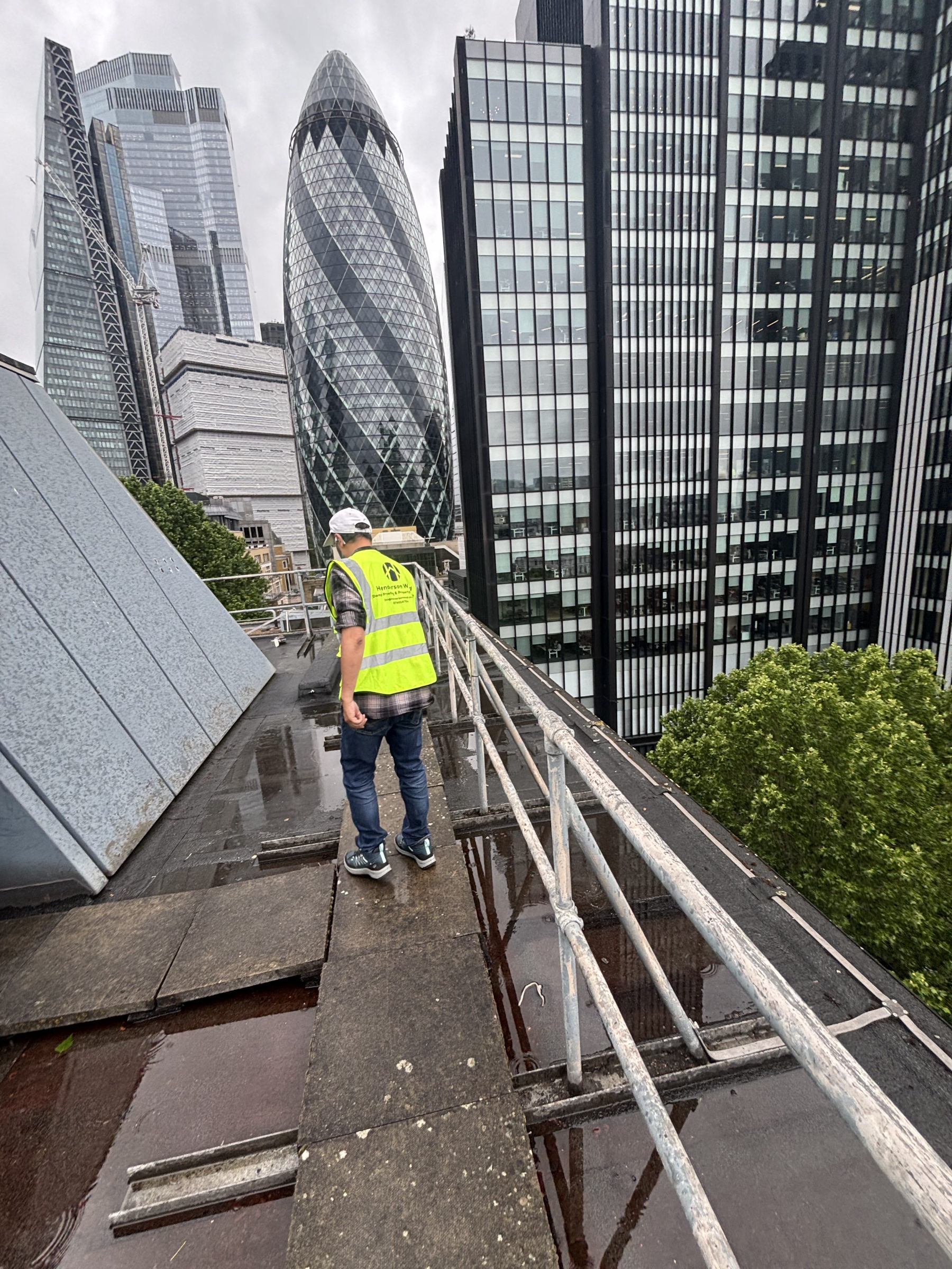 Henderson Wood surveyor on a commercial rooftop in the City of London near the Gherkin